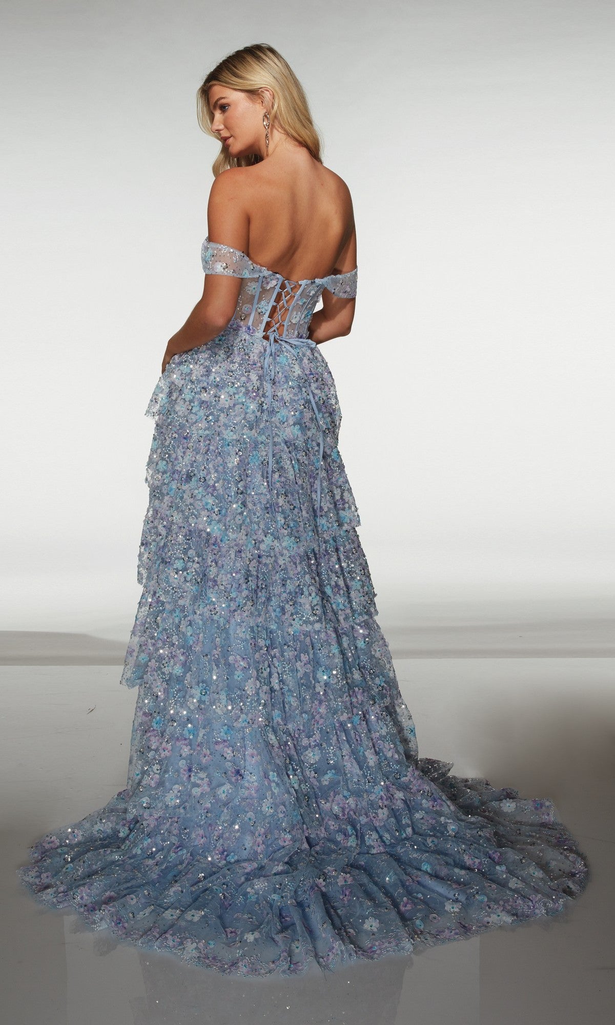 A woman wearing the Alyce 62186 long prom dress in blue, featuring an off-the-shoulder design and delicate 3D floral appliques.